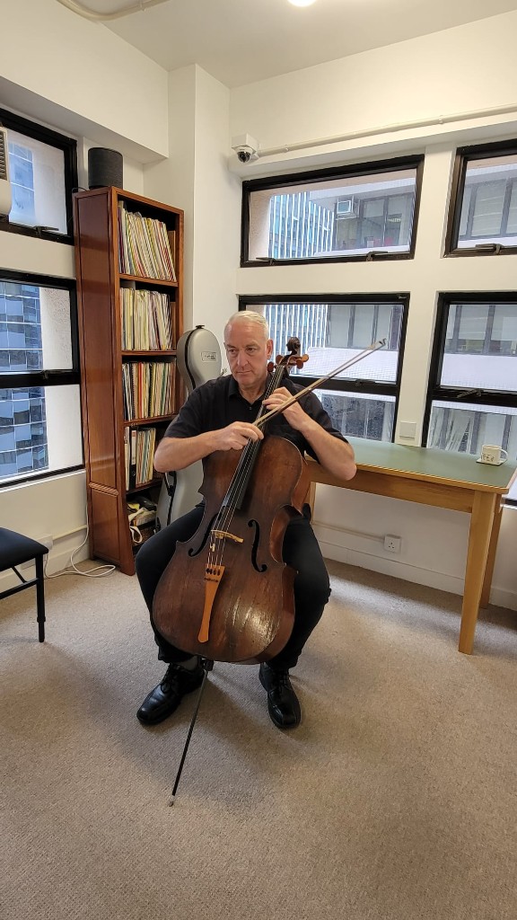Ron Wilson playing cello in his Hong Kong Strings studio